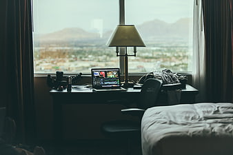 Hotel room workspace with laptop, camera, and city view