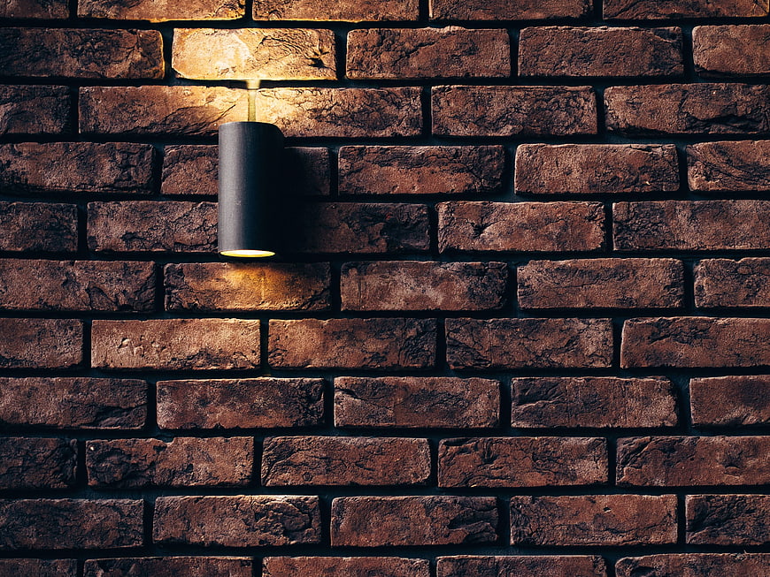Modern black sconce on textured brick wall background