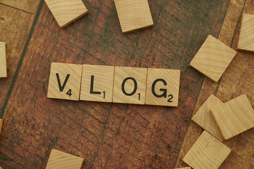 Vlog spelled with wooden Scrabble tiles on rustic background