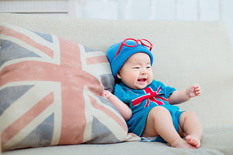 Happy baby in blue outfit with Union Jack pillow