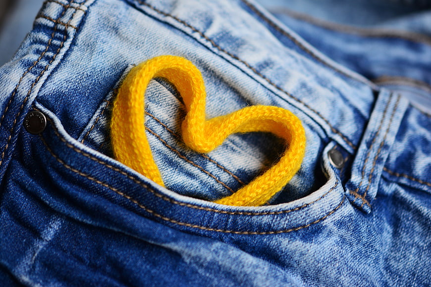 Yellow yarn heart in blue jeans pocket