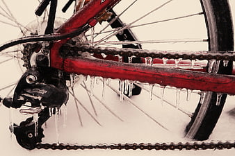Frozen red bicycle chain and gears covered in icicles