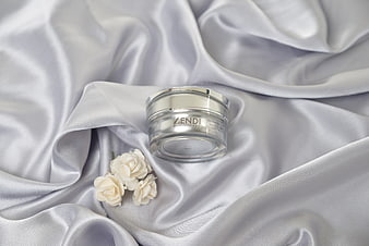 Luxury skincare jar on white silk with jasmine flowers