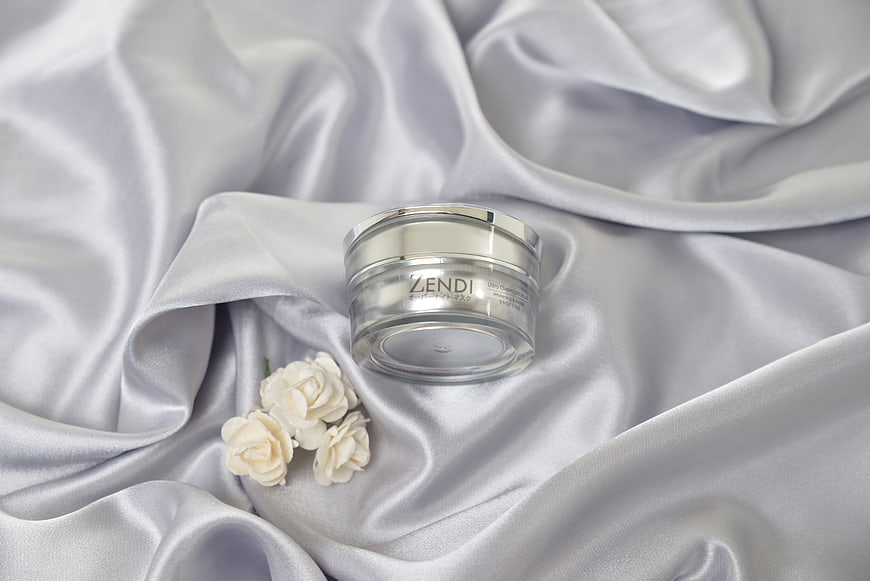 Luxury skincare jar on white silk with jasmine flowers