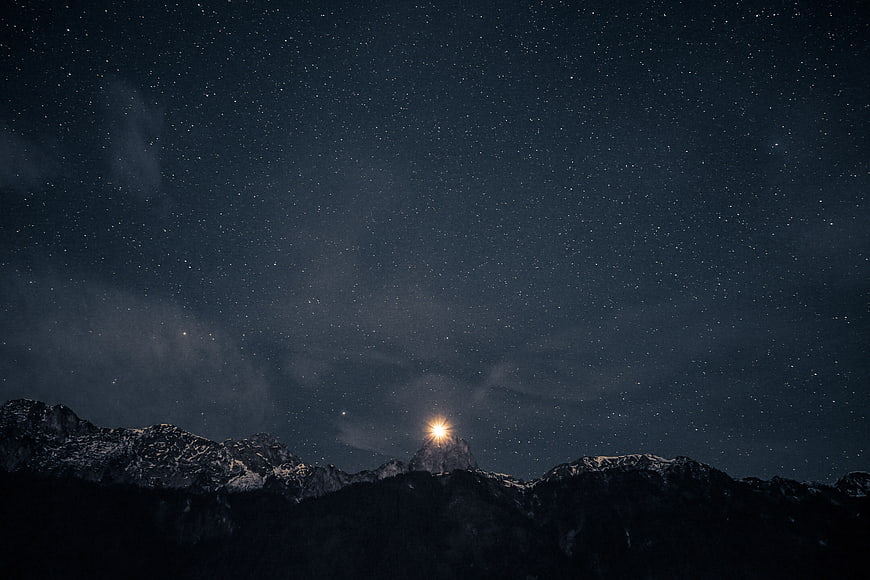 Starry Night Sky Over Snowy Mountain Peaks