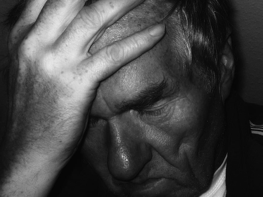 Black and white portrait of a distressed man holding his head