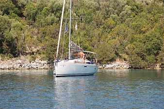 Sailboat Anchored in Mediterranean Cove with Man on Deck