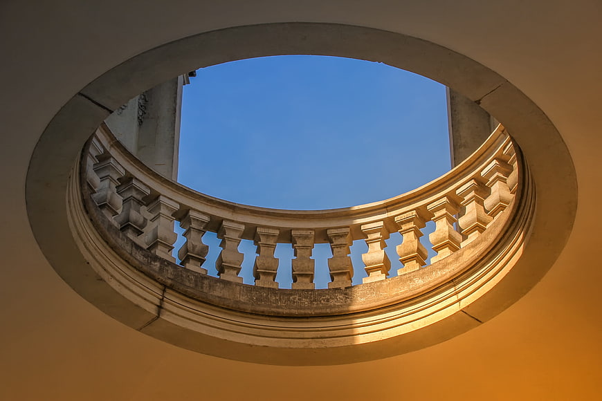 Circular architectural opening with stone balustrade against blue sky