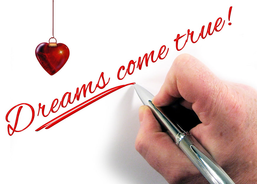 Hand writing dreams come true with red pen and heart