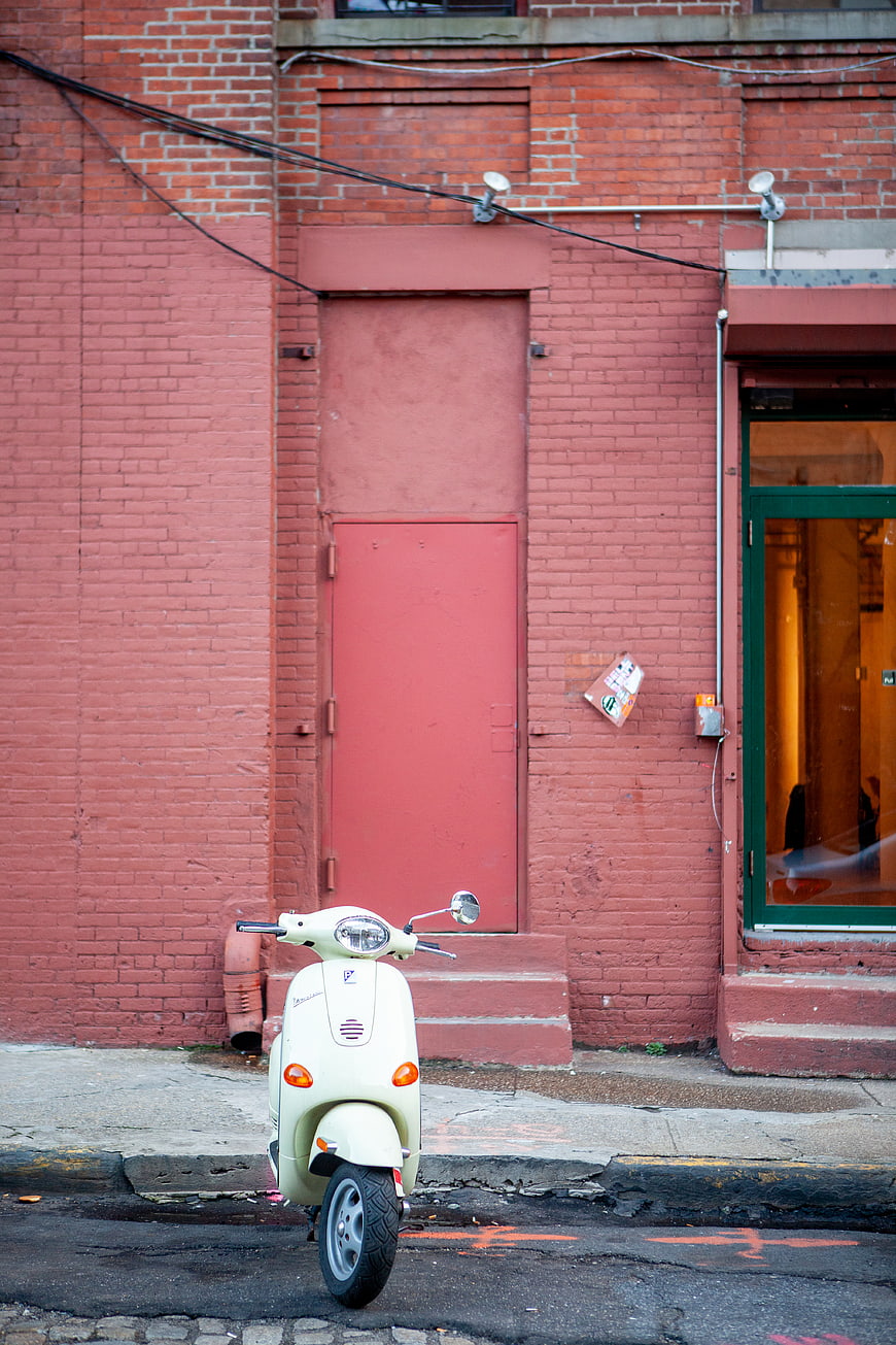 Cream Scooter Parked Against Red Brick Wall