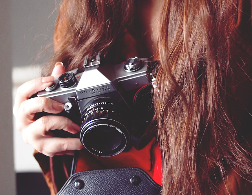 Close-up of woman holding vintage Praktica SLR camera