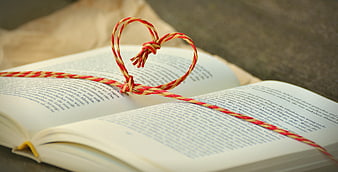 Red and yellow string heart on open book pages
