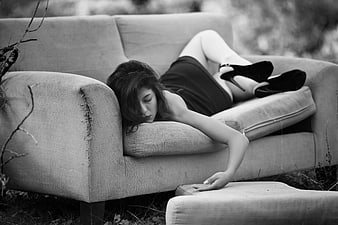 Black and white portrait of a woman lying on an outdoor sofa