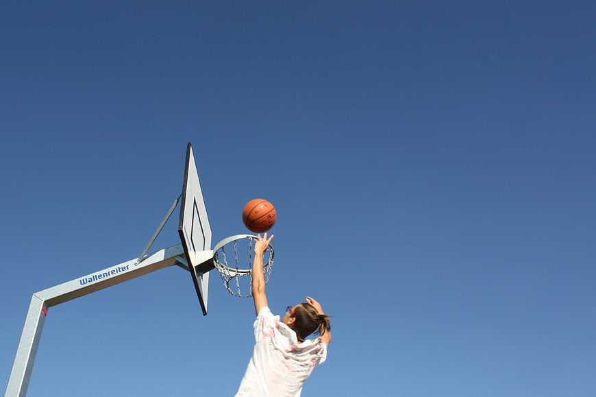 Woman Dunking Basketball Against Blue Sky