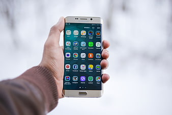 Hand holding gold Samsung smartphone in snowy winter
