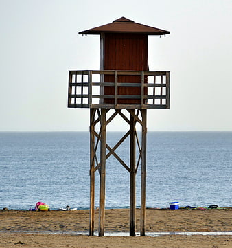 Wooden Lifeguard Tower on Sandy Beach with Ocean Background