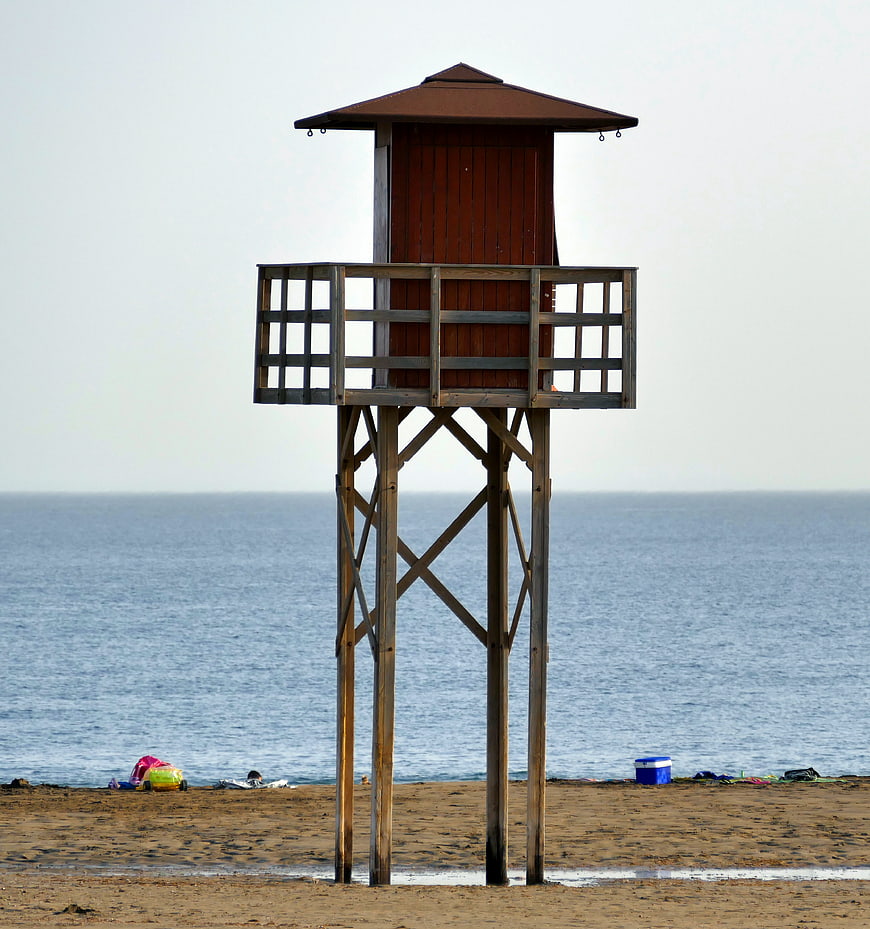 Wooden Lifeguard Tower on Sandy Beach with Ocean Background