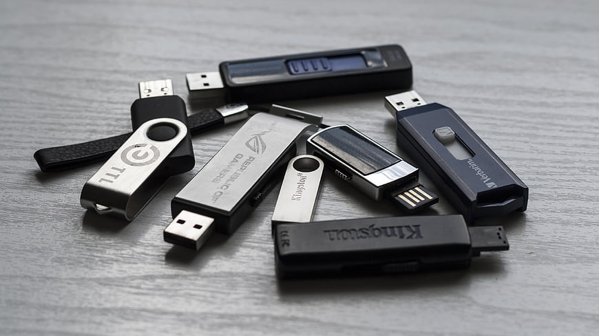 Collection of various USB flash drives on gray wood