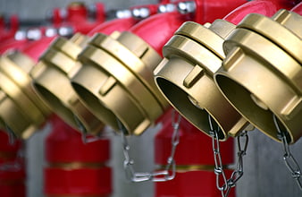 Close-up of red fire hydrants with brass caps and chains