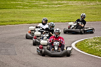 Four Drivers Racing Go Karts On Outdoor Track
