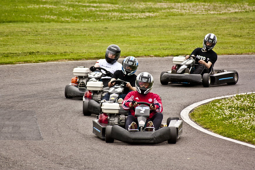Four Drivers Racing Go Karts On Outdoor Track