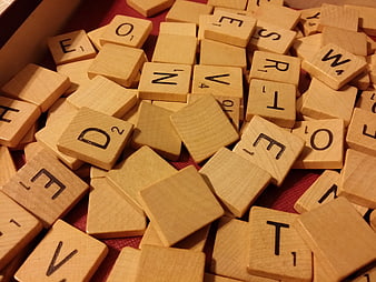 Close-up of wooden Scrabble letter tiles scattered on a red felt surface