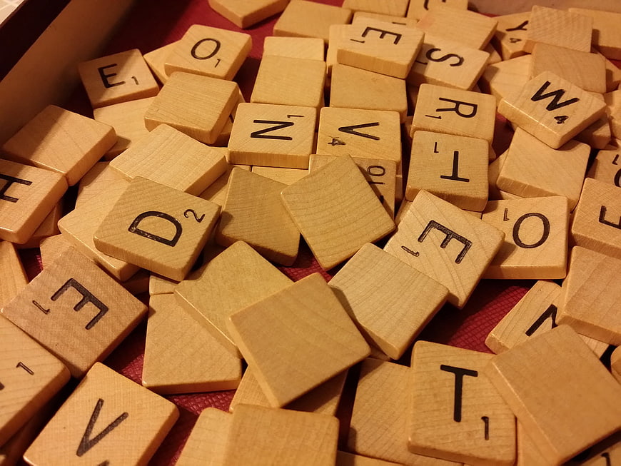 Close-up of wooden Scrabble letter tiles scattered on a red felt surface