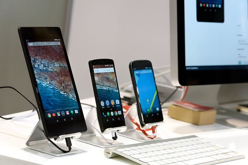 Android smartphones and tablet on display stands with keyboard and monitor