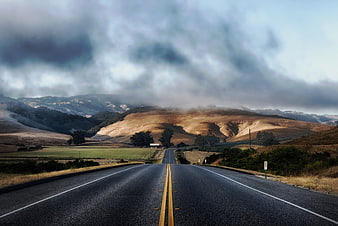 Winding Highway Through Golden Hills Under Dramatic Clouds