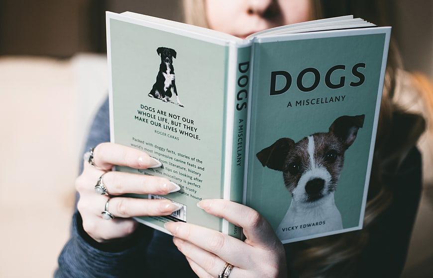 Woman Reading Book About Dogs with Cute Puppy Cover