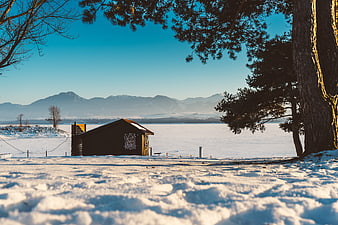 Rustic wooden cabin on frozen lake with mountains