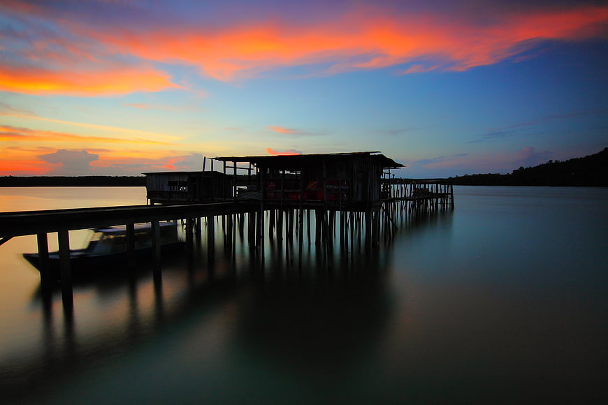Silhouette of wooden stilt house on pier at sunset