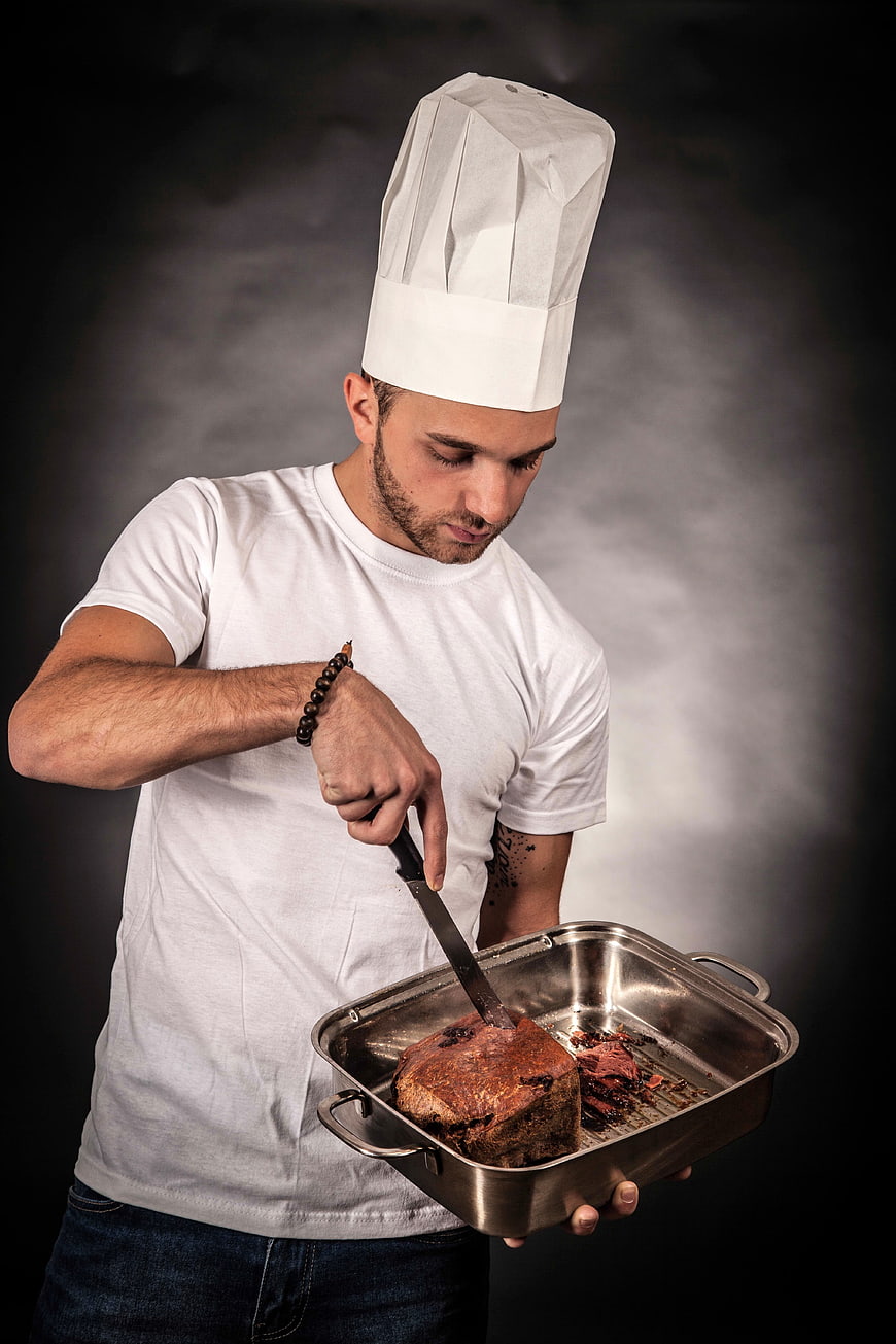 Chef Slicing Roasted Meat in Pan