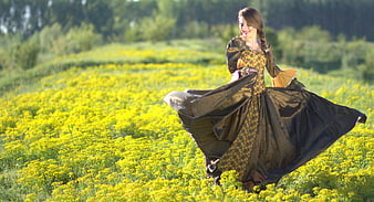 Woman in Traditional Dress Spinning in a Field of Yellow Wildflowers