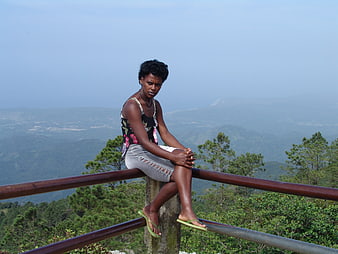 Woman sitting on railing overlooking mountain landscape