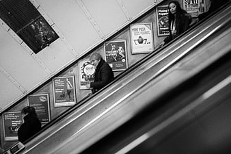 Black and white photo of people on escalator in subway station