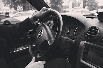 Black and white photo of hands on Mercedes steering wheel