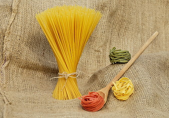Assorted raw pasta nests on rustic burlap background