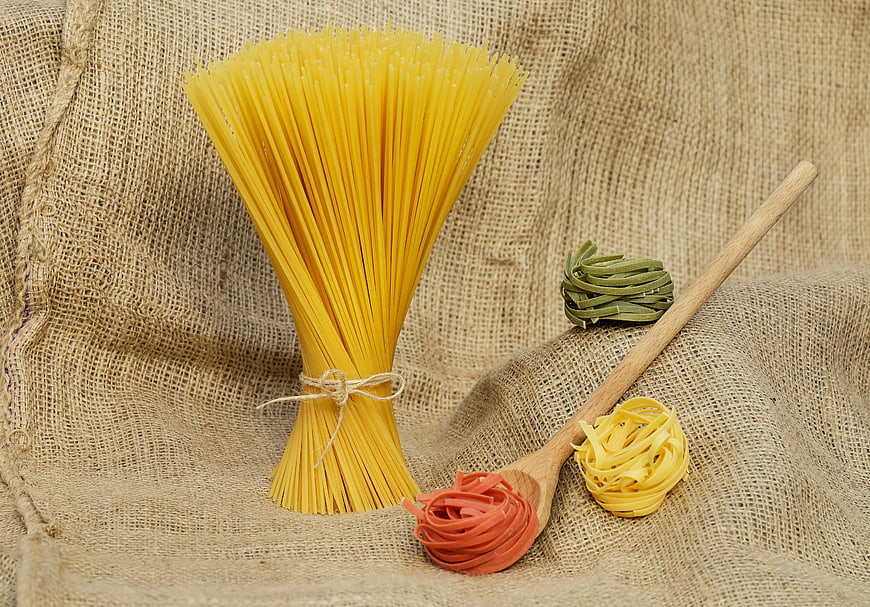 Assorted raw pasta nests on rustic burlap background