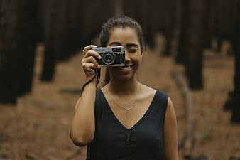 Happy woman holding vintage camera in forest
