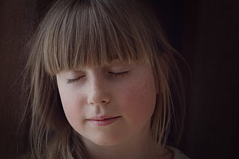 Close-up portrait of a young girl with closed eyes and freckles