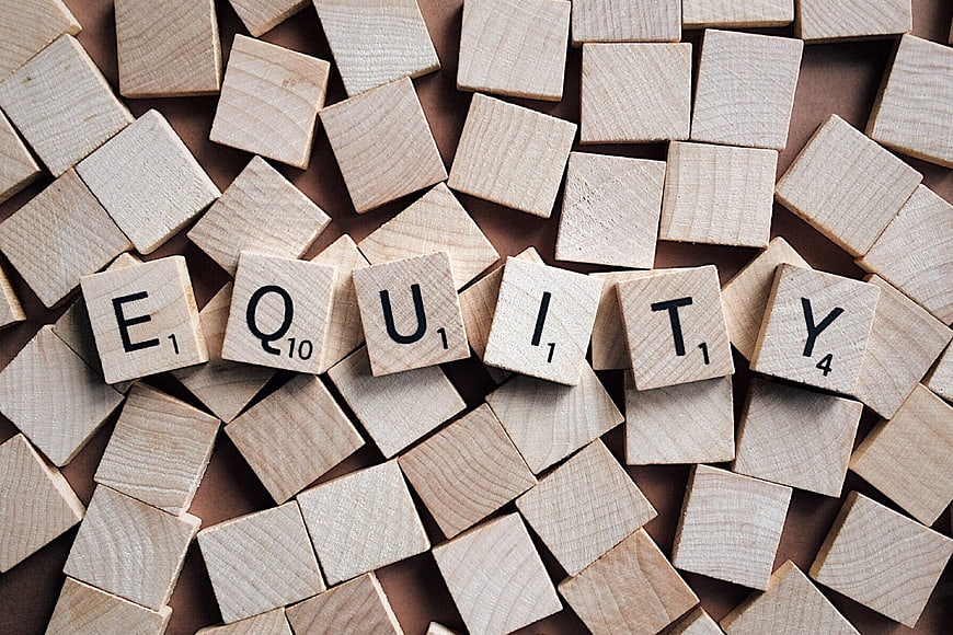 Wooden Scrabble Tiles Spelling Equity on Brown Background