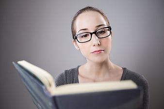 Young woman with glasses reading a book