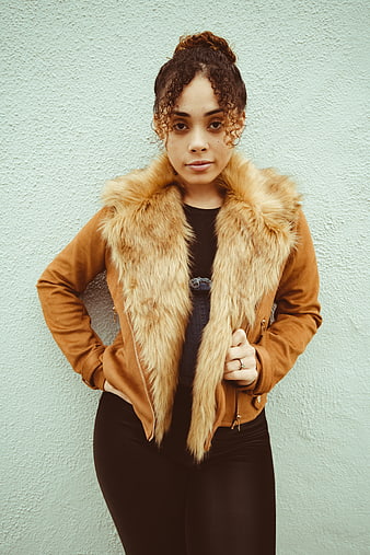 Confident Woman in Brown Fur Jacket Against Textured Wall