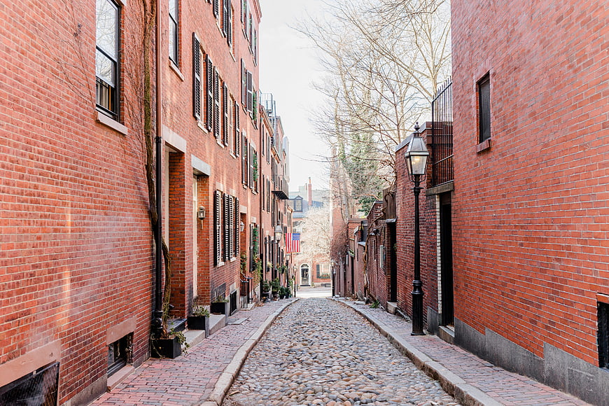 Historic cobblestone alleyway between red brick buildings