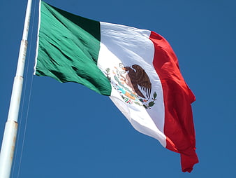 Mexican flag waving against a clear blue sky