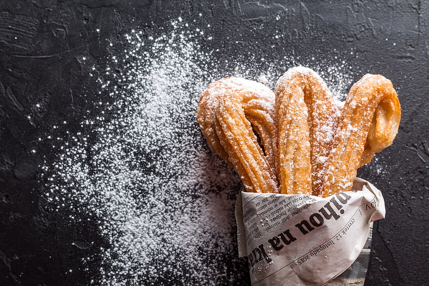 Churros with Powdered Sugar on Dark Background