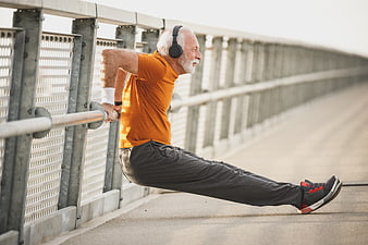 Senior man doing tricep dips on bridge railing