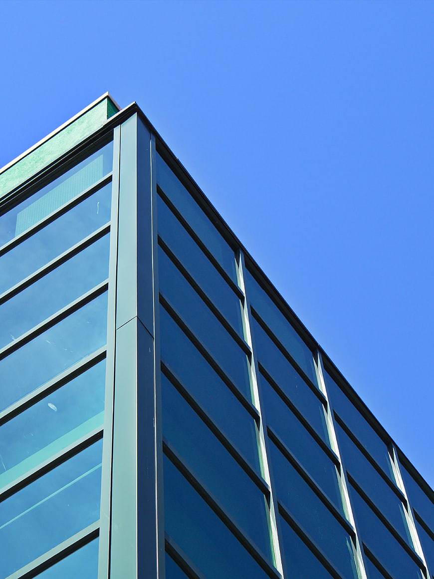 Modern Glass Office Building Corner Against Blue Sky
