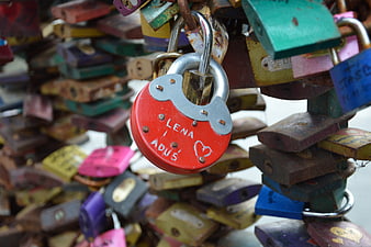 Red heart-shaped love padlock with names engraved on bridge